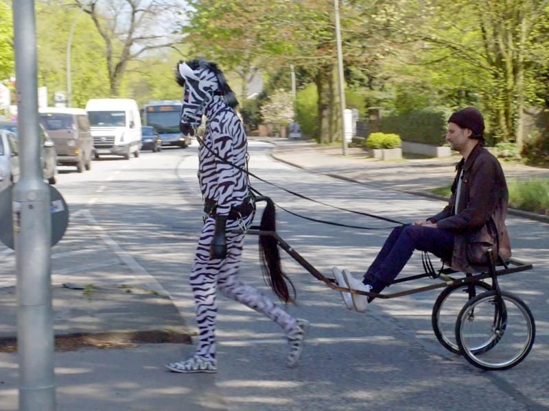 Das Zebra (Klaus, Informatiker) zieht den Rabiat-Reporter Manuel Möglich auf einem Sulky durch Hamburg Altona. Foto: Radio Bremen/Matthias Bähr