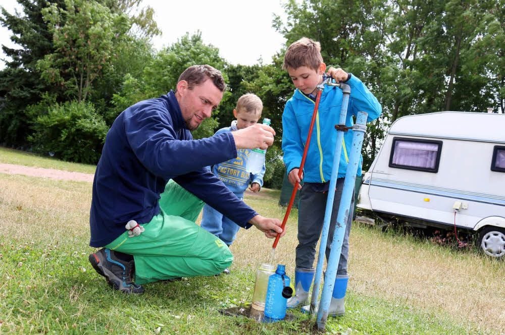 Stefan Müller füllt mit seinen Kindern Carl und Linus (v. l.) den Trinkwasservorrat nach.
