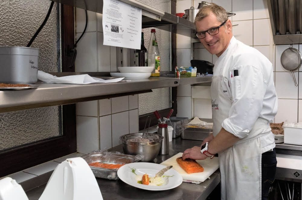 Steffen Warias schneidet gerade die Lachsfilets für den Vorspeise-Teller seines acht Gänge umfassenden Silvestermenüs.