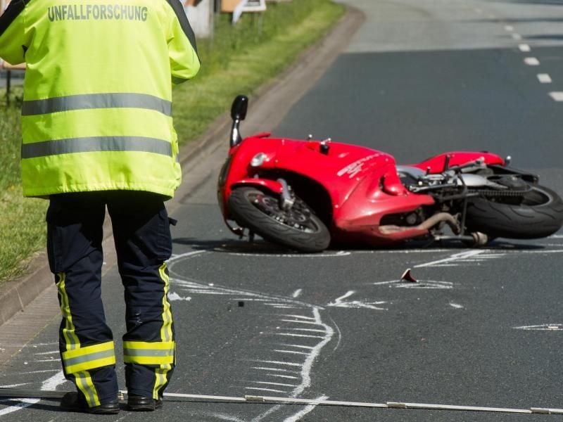 Ein Unfallforscher untersucht ein Motorrad an einer Unfallstelle. Foto: Julian Stratenschulte/Archiv