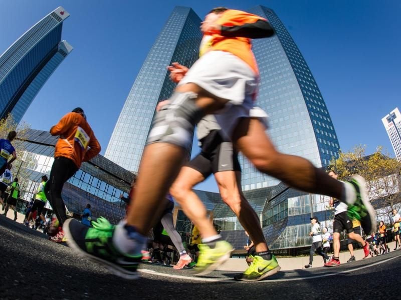 Teilnehmer des Frankfurt-Marathons 2016 laufen an Hochhäusern vorbei. Foto: Christoph Schmidt/Archiv