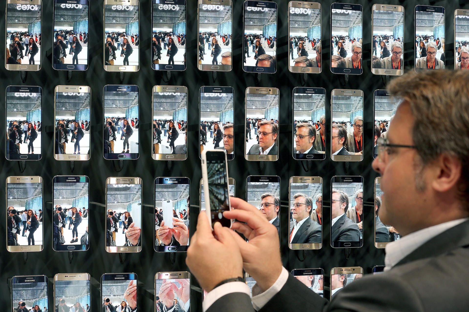 Ein Journalist fotografiert während einer Pressekonferenz von Samsung auf der Funkausstellung in Berlin eine Präsentationswand mit Smartphones der Marke Galaxy S6 edge.