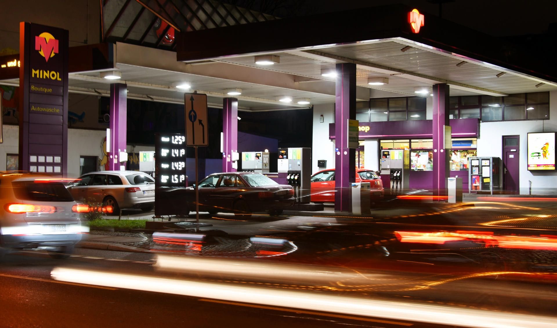 An der in den Farben lila-gelb leuchtenden Minol-Tankstelle im Leipziger Westen fahren Autos vorbei.