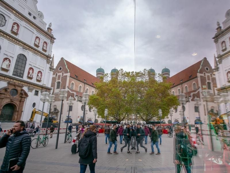 Die Kaufingerstraße in der Innenstadt spiegelt sich in der großen Glasscheibe eines Kaufhaus. Foto: Peter Kneffel/dpa/Archivbild