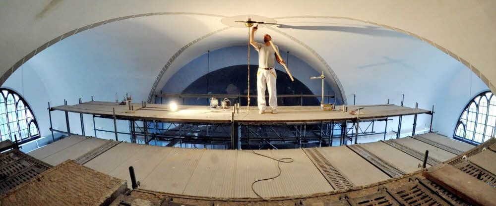 Malermeister Hagen Meißner aus Landsberg steht ganz oben auf dem Gerüst, um die Decke zu malern.