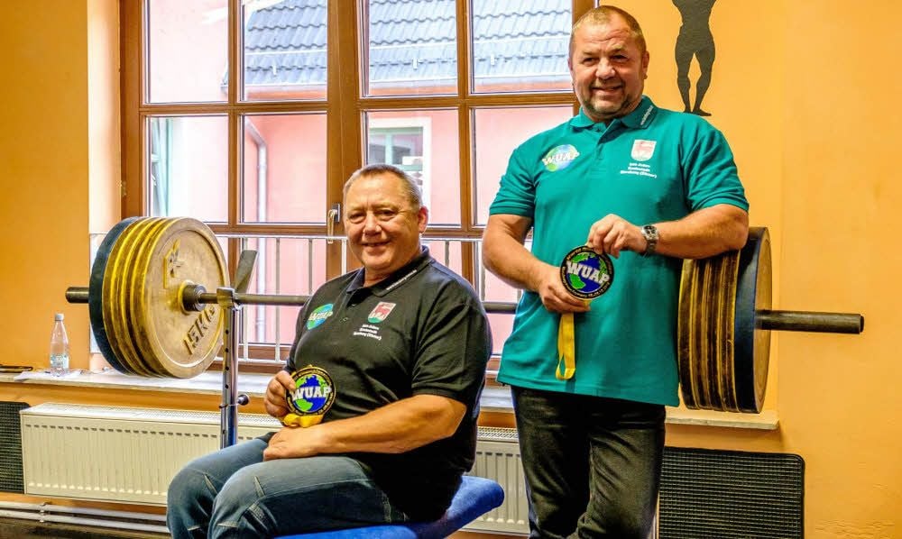 Klaus Grosser (li.) und Falk Steinkopf zeigen ihre WM-Goldmedaillen in der Trainingsstätte an der Hantelbank.