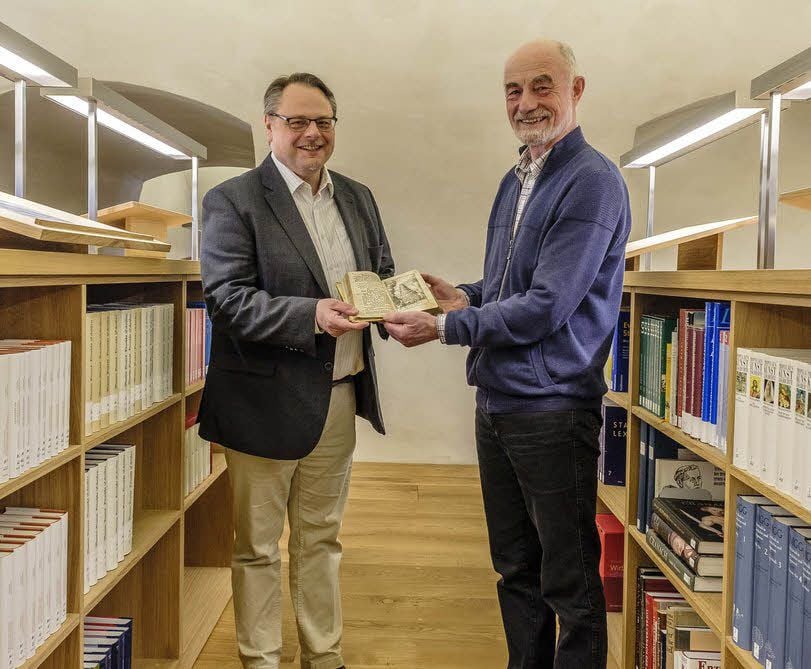 Beschenkt: Matthias Meinhardt (l.) leitet die neue Reformationsgeschichtliche Forschungsbibliothek in Wittenberg. Die ist seit Montag um ein weiteres Buch reicher, das Friedemann Ehrig als Schenkung in den Bestand gibt.