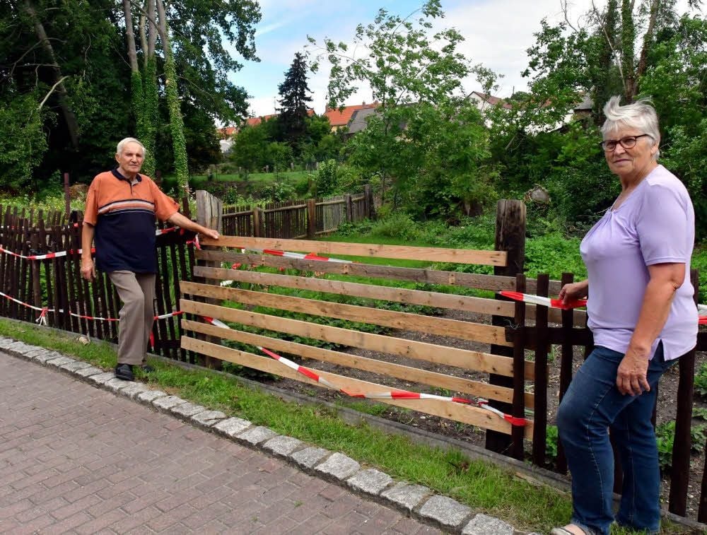 Gisela und Werner Kuckuk vor dem provisorisch geschlossenen Zaun, auf den die Bäume gefallen sind.