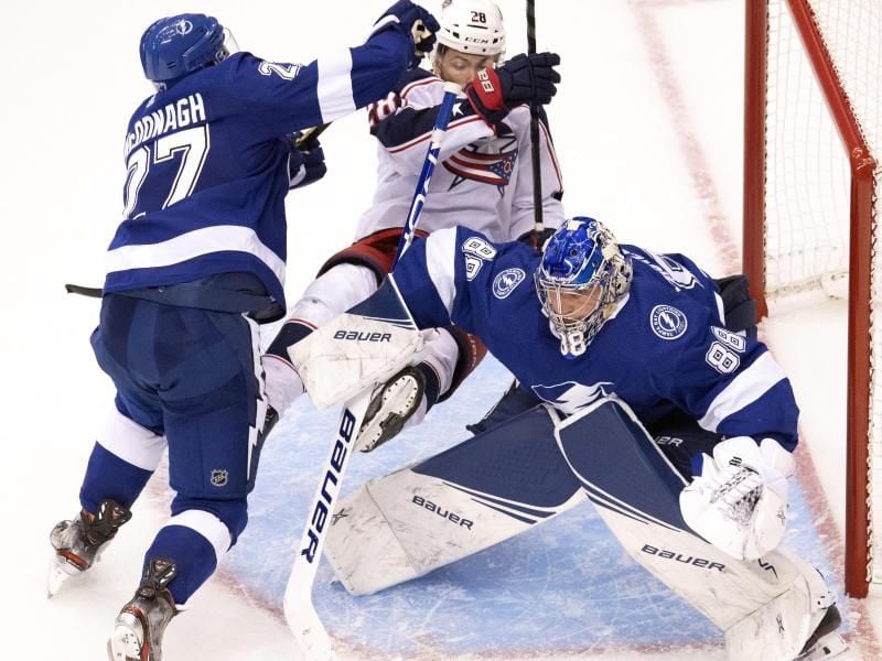 Tampa Bays Verteidiger Ryan McDonagh (l) prallt mit Oliver Bjorkstrand (M) von den Blue Jackets und seinem Torwart Andrei Wassilewski (r) vor dem Tor zusammen. Foto: Frank Gunn/The Canadian Press/dpa