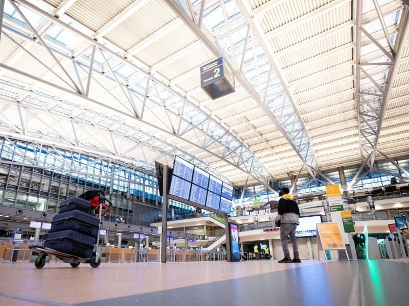 Ein Fluggast steht vor der Anzeigetafel in der Abflughalle im Terminal 2 am Flughafen Hamburg. Foto: Christian Charisius/dpa/Archivbild