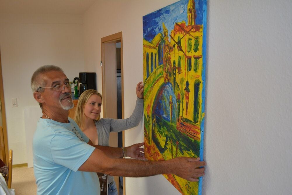 Mandy Reinhardt und Joachim Patzer hängen das Venedig-Bild von Michael Patzer auf.