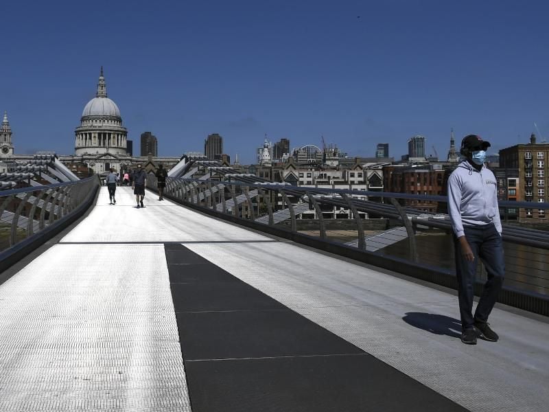 Ein Mann mit Mundschutz überquert während der anhaltenden Ausgangsbeschränkungen die fast menschenleere Millennium Bridge in London. Foto: Alberto Pezzali/AP/dpa