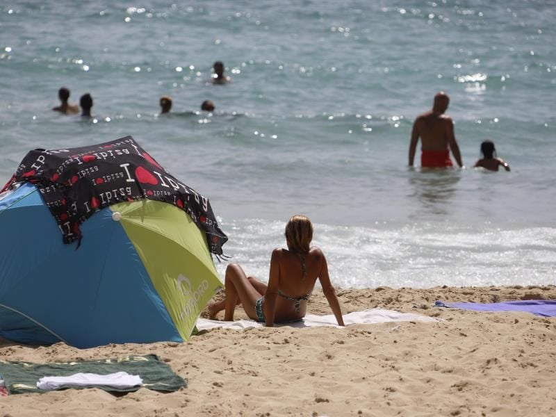 Eine Frau sonnt sich am Strand von Cala Major. Foto: Clara Margais/dpa