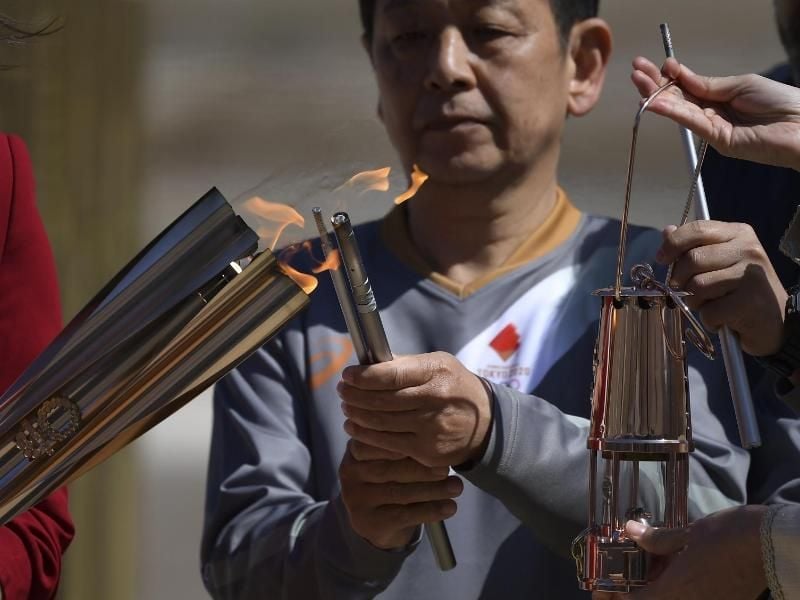 Die olympische Fackel wird während der Übergabe des olympischen Feuers an die Organisatoren der Sommerspiele von Tokio entzündet. Foto: Aris Messinis/AFP POOL/AP/dpa