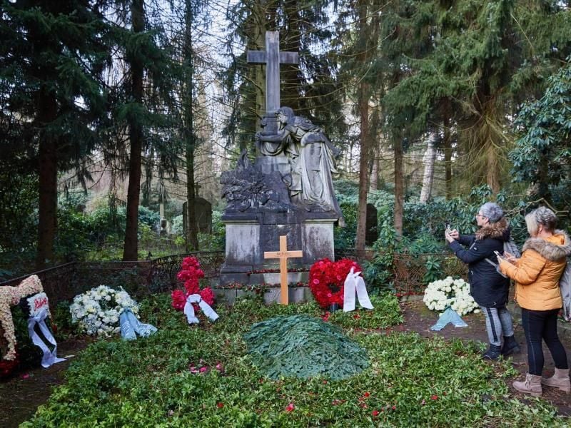 Zwei Frauen stehen am Grab von Jan Fedder auf dem Ohlsdorfer Friedhof. Foto: Georg Wendt/dpa