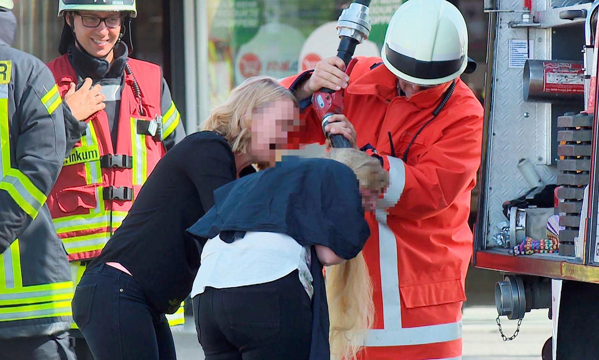 Kurioser Einsatz: Ein Feuerwehrmann wäscht einer Friseurkundin mit Wasser aus dem Schlauch die Haare aus.