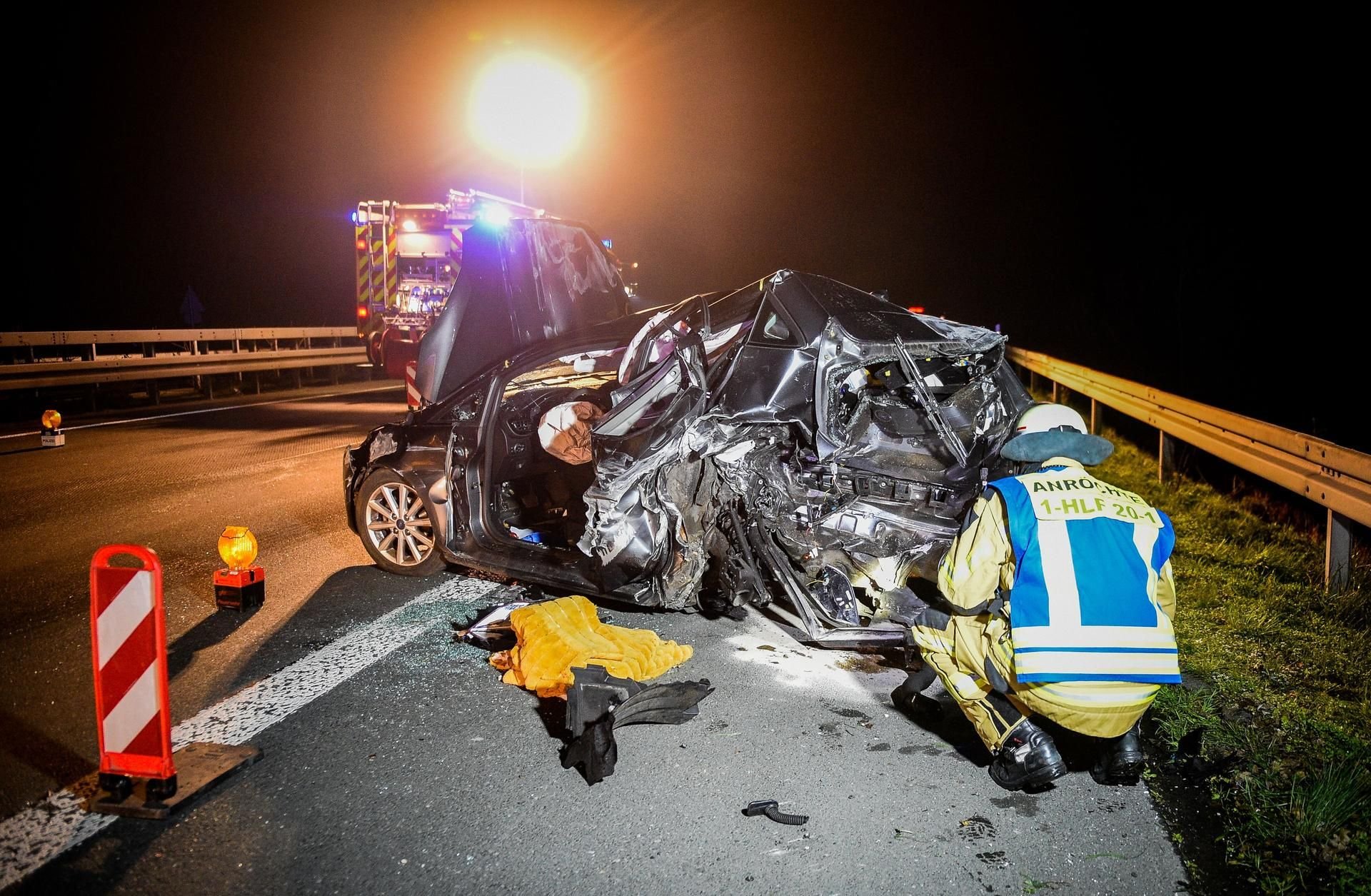 Ein Feuerwehrmann kniet neben einem Unfallfahrzeug. Eine Frau ist nach einem Zusammenstoß zweier Autos auf der Autobahn 44 bei Anröchte (Kreis Soest) gestorben.