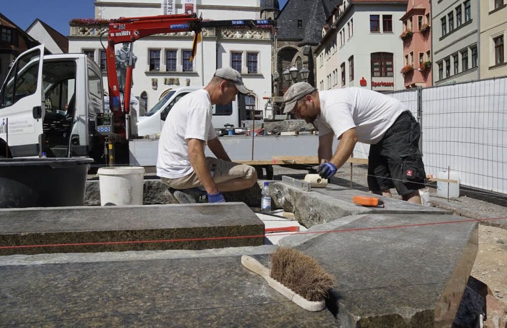 Guido Hecker und Ralf Herzog von den Werkstätten für Denkmalpflege verlegen die ersten Granit-Stufen des Sockels.