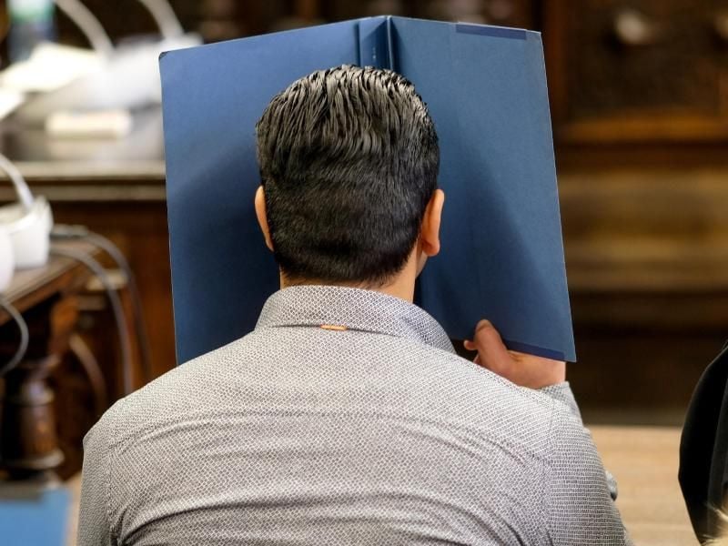 Der Angeklagte verdeckt im Gericht sein Gesicht mit einem Aktenordner. Foto: Axel Heimken