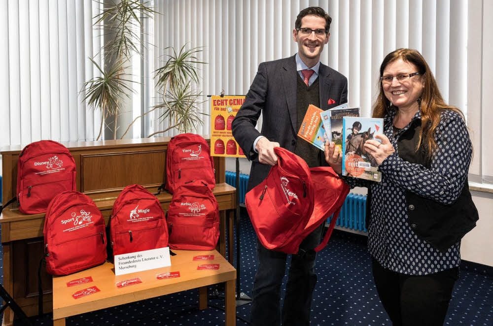 Martin Popp vom Freundeskreis Literatur übergibt Kinderbibliothekarin Anke Feineis die Leserucksäcke.