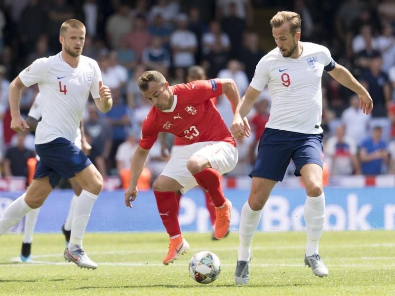 Xherdan Shaqiri (M) aus der Schweiz im Zweikampf mit Harry Kane. Foto: Jean-Christophe Bott/KEYSTONE