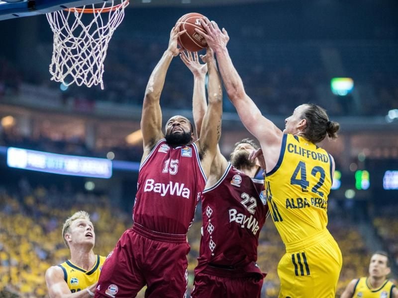 Die Bayernspieler Reggie Redding (l) und Danilo Barthel (M) wehren den ball von ALBA Berlins Dennis Clifford ab. Foto: Jens Büttner