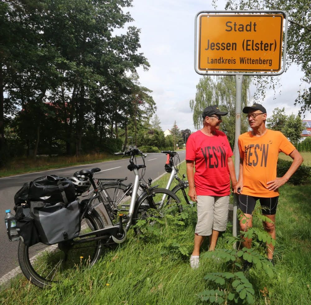 Barbara und Olaf Jessen haben sich fürs Erinnerungsfoto das Ortsschild in der Annaburger Straße ausgesucht. Man beachte die von einem ihrer Söhne gestalteten T-Shirts mit der Aufschrift „Yes’n“, Jessen international sozusagen.