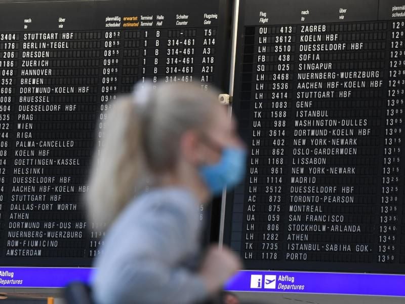 Eine Frau mit Mundschutz im Terminal 1 des Frankfurter Flughafens. Foto: Arne Dedert/dpa/Archivbild