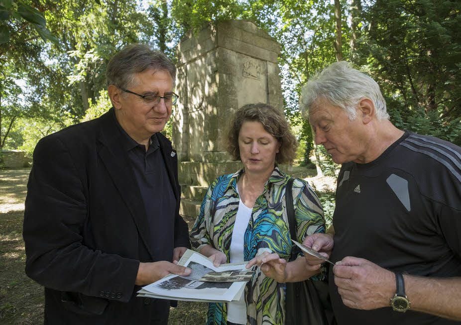 Klaus Wycisk, Angela Krug und Rolf Zogbaum (v.l.) schauen sich alte Fotos an aus der Zeit, als das Denkmal eingeweiht wurde.