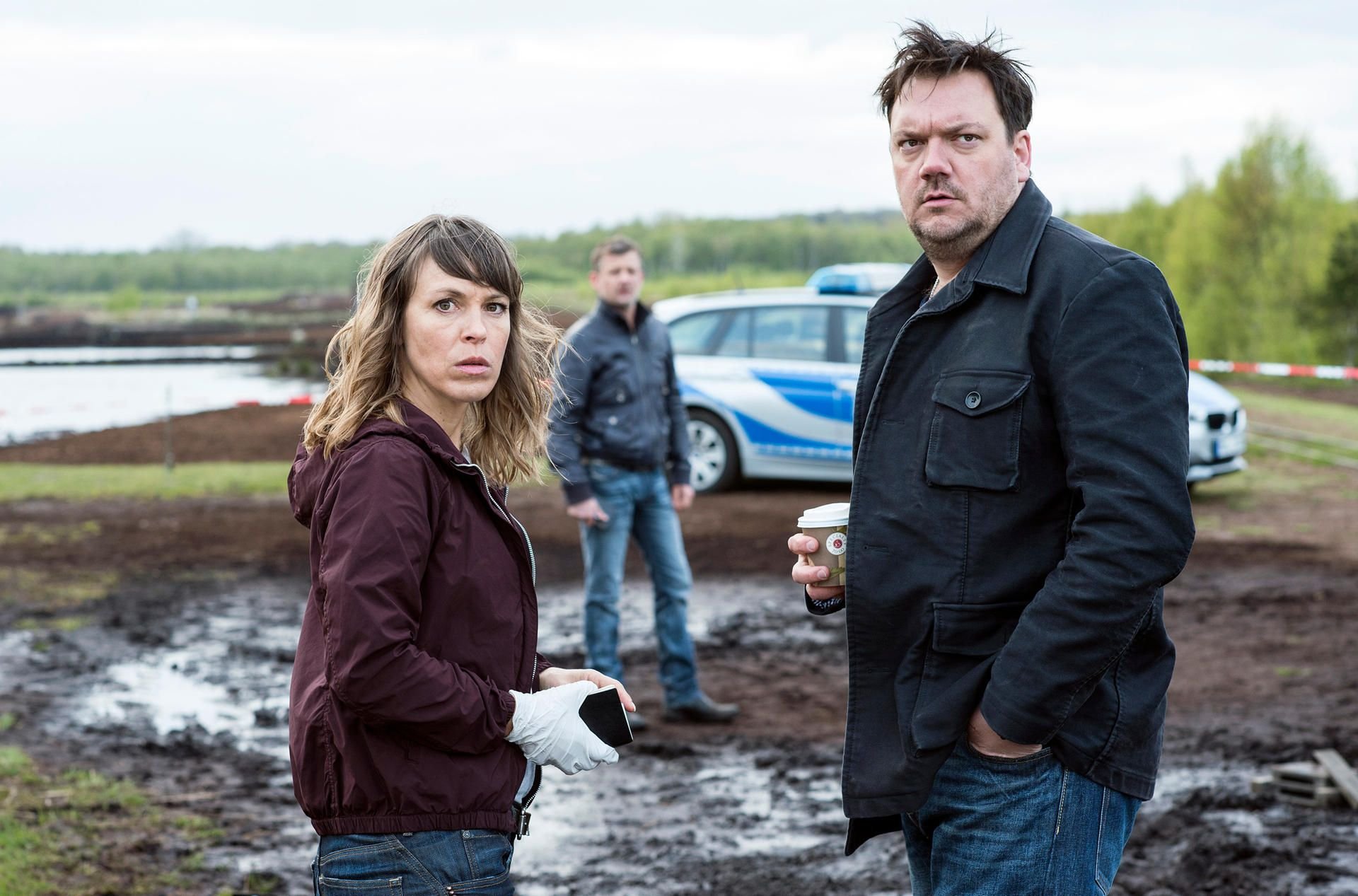 Die Kommissare Katrin König (Anneke Kim Sarnau), Alexander Bukow (Charly Hübner, r) und Anton Pöschel (Andreas Guenther, Hintergrund) stehen am Tatort - eine Szene des Krimis «Polizeiruf 110: In Flammen».