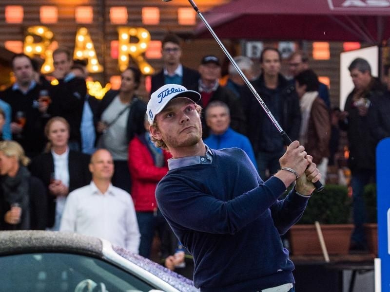 Niklas Adank schlägt in Hamburg auf dem Spielbudenplatz einen Golfball. Foto: Christophe Gateau