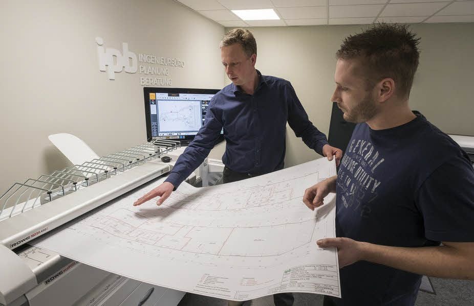 Firmeninhaber André Drachau (links) und Statiker Mathias Gebhardt mit einem frisch gedruckten Bauplan.