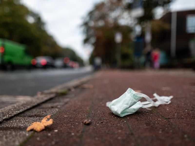 An einer Straße liegt ein Mund-Nasen-Schutz auf dem Boden. Foto: Fabian Strauch/dpa/Archiv
