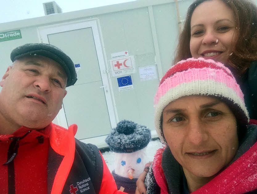 Diese Vierer-Gruppe ist eines der letzten Bilder, die Martin Steinert (links) vor seiner Rückkehr im Norden Griechenlands, im winterlichen Flüchtlingslager Kordelio, vor der dortigen kleinen Container-Klinik, aufnahm. Mit abgelichtet sind hier eine Rot-Kreuz-Mitarbeiterin und eine griechische Kinderärztin sowie ein Schneemann mit echt kurdischer Kopfbedeckung.
