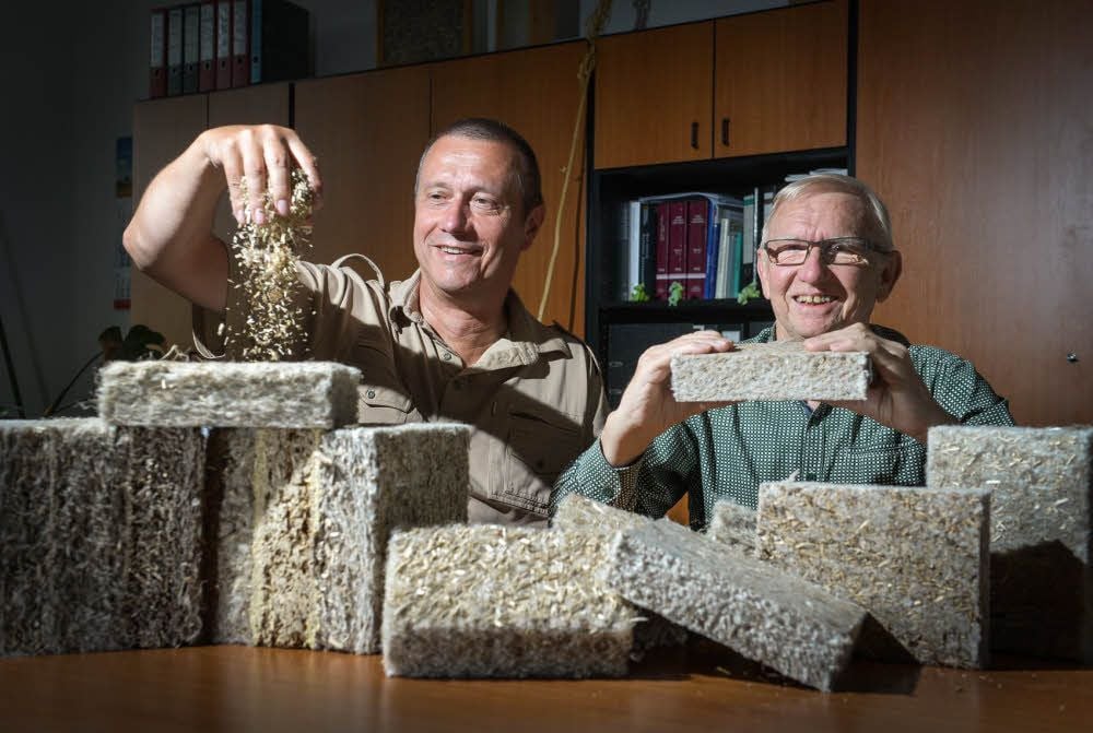 Andreas Rauer (l.) und Herbert Hartung präsentieren Dämmstoffteile aus der Testproduktion. Was durch Rauers Hand rieselt, sind die Hanfschäben. Bislang werden sie als Einstreu in Ställen verwendet. Künftig sollen sie mit verarbeitet werden.