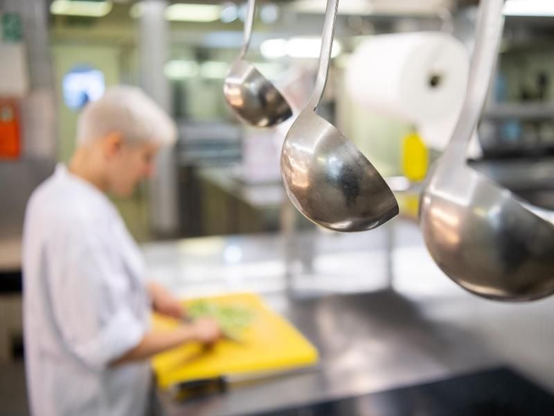 Eine Auszubildende arbeitet in einem Hotel in der Küche eines Restaurants. Foto: Sebastian Gollnow/Illustration
