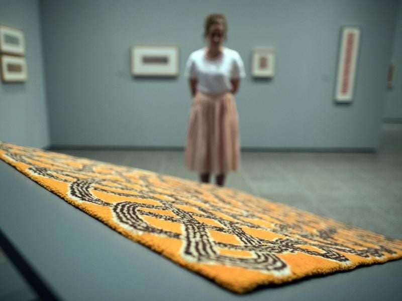 Eine Mitarbeiterin der Kunstsammlung NRW betrachtet einen Teppich, der von Anni Albers gestaltet wurde. Foto: Federico Gambarini