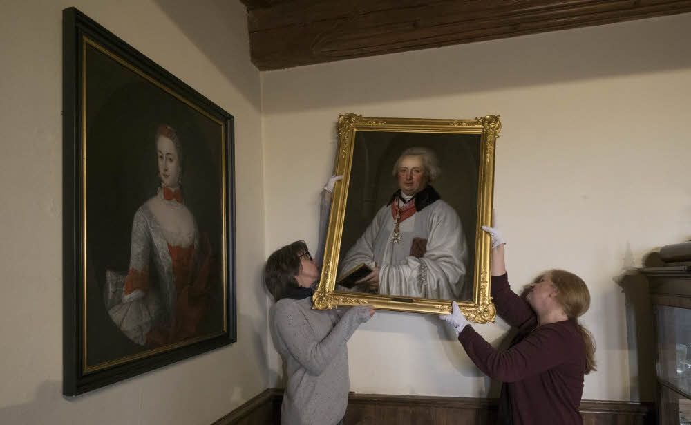 Marita Geisler (l.) und Restauratorin Andrea Himpel hängen das Porträt von August Ludwig Busso II. von der Asseburg auf.