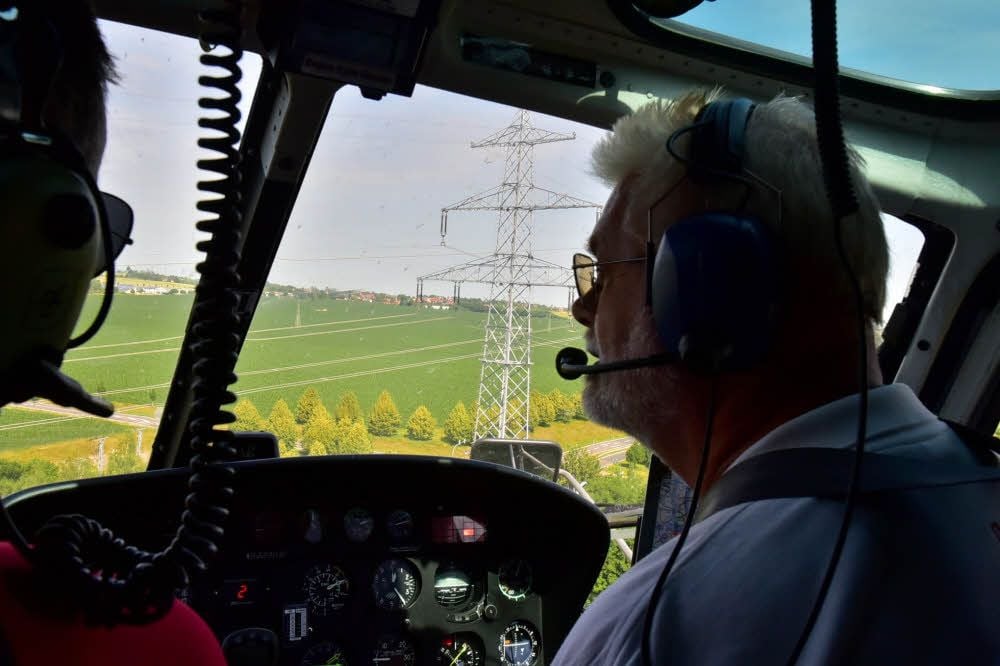 Pilot Siegfried Lange steuert den Helikopter so nah wie möglich und langsam an die Masten und Leitungen.