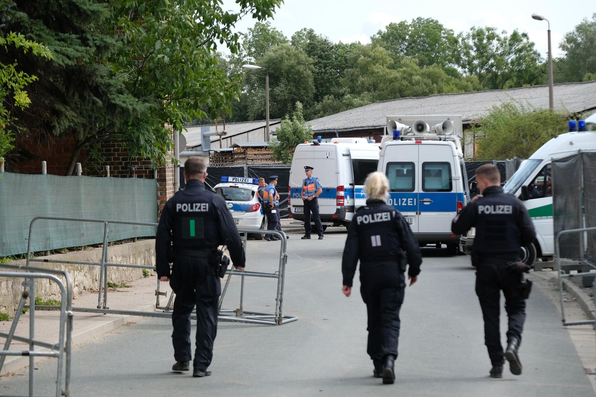 Polizisten gehen durch eine mit Absperrgittern blockierte Straße entlang. In dem kleinen Dorf war ein Neonazi-Konzert mit mehreren Tausend Teilnehmern geplant,