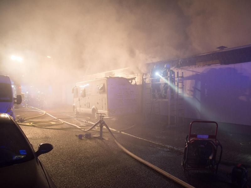 Feuerwehrleute bekämpfen ein Feuer an Reihenhäusern und einem, vor den Gebäuden geparktem, Wohnmobil in Hattersheim. Foto: Wiesbaden112.de