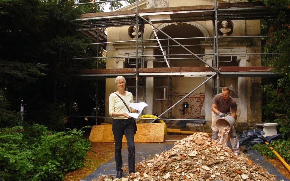 Das wird wieder: Annette Scholtka mit Unterlagen vor der Baustelle des Englischen Sitzes.