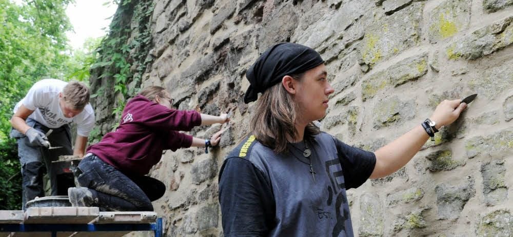 Verfugen für den guten Zweck - und die Selbsterfahrung: Andreas Hinrichs , Laura Dunse und Egor Yushchenko (v.r.) arbeiten an Schloss Mansfeld.