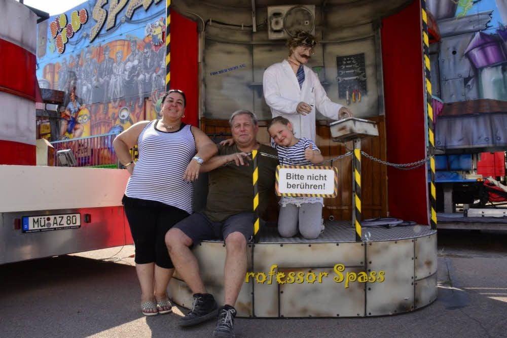 Monika und Alwin Zinnecker mit Enkelin Laura und Professor Spaß vor ihrem Fahrgeschäft.