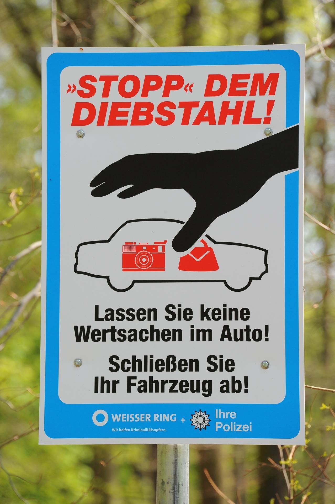 Ein Schild der Polizei erinnert Autofahrer daran, ihre Fahrzeuge abzuschließen und keine Wertgegenstände liegenzulassen.