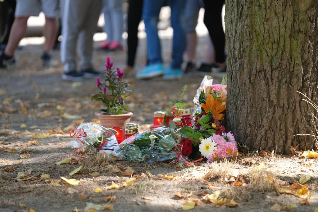 Köthen: Blumen und Kerzen stehen an einem Baum auf einem Spielplatz.