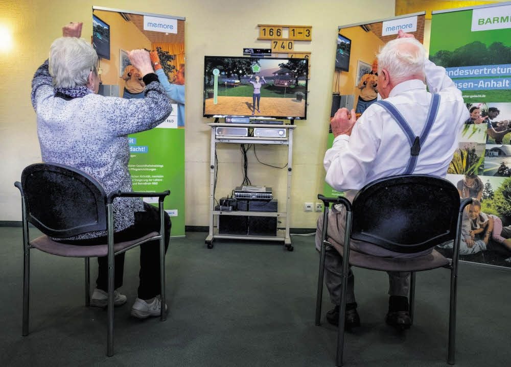Erika Tomas, 91 Jahre, und Wilhelm Ihl, 96 Jahre, trainieren spielerisch mit der MemoreBox ihr Koordinationsvermögen. Eine Kamera filmt ihre Bewegungen.