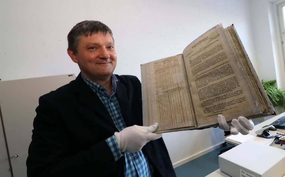 Ulrich Seifert zeigt die „Seelenliste“ von 1808. Restauratoren haben das alte Papier schon mit neuen Seiten hinterlegt, um es vor dem Zerfall zu bewahren.