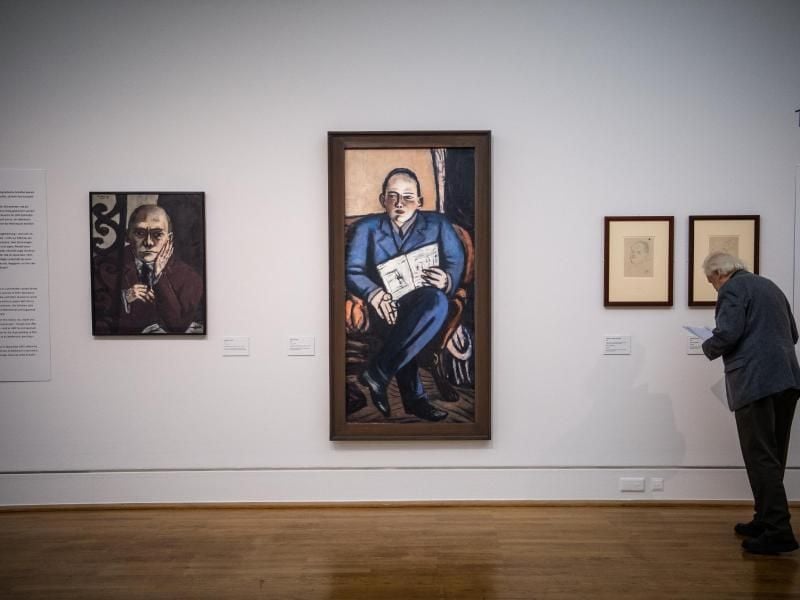 Ein Mann steht vor Gemälden des Künstlers Max Beckmann (1884-1950). Foto: Arne Immanuel Bänsch/dpa/Archivbild