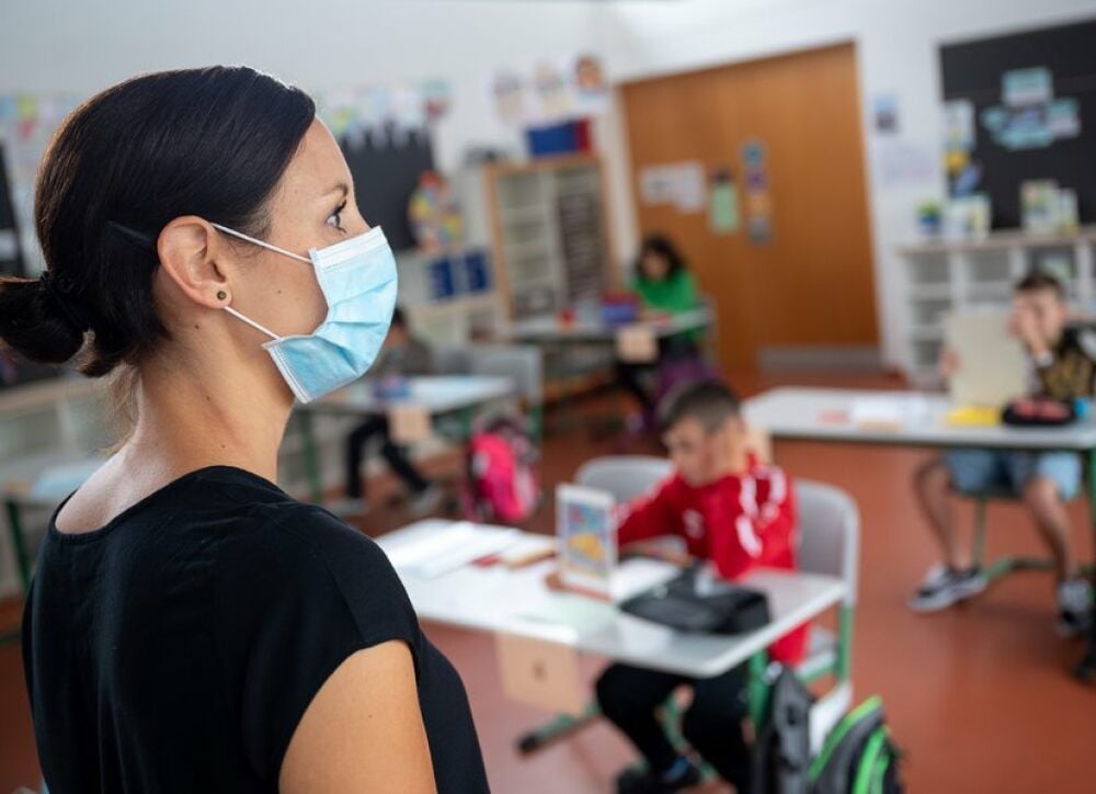 Eine Lehrerin unterrichtet mit Mundschutz.